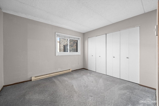 unfurnished bedroom featuring a closet, baseboards, carpet, and a baseboard radiator