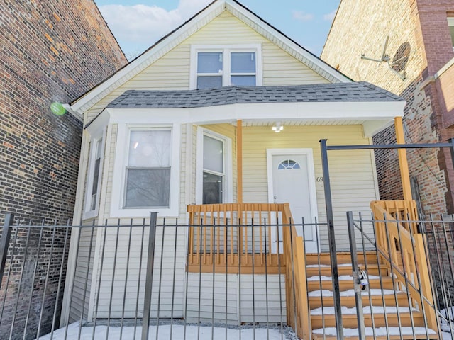 view of front of home with a fenced front yard, a porch, and a shingled roof