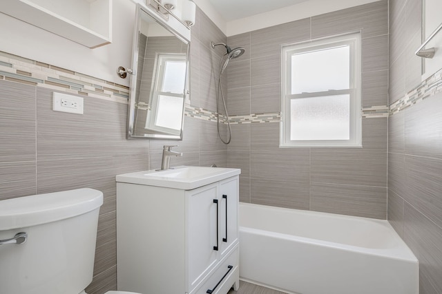 bathroom featuring tile walls, toilet, bathing tub / shower combination, and vanity
