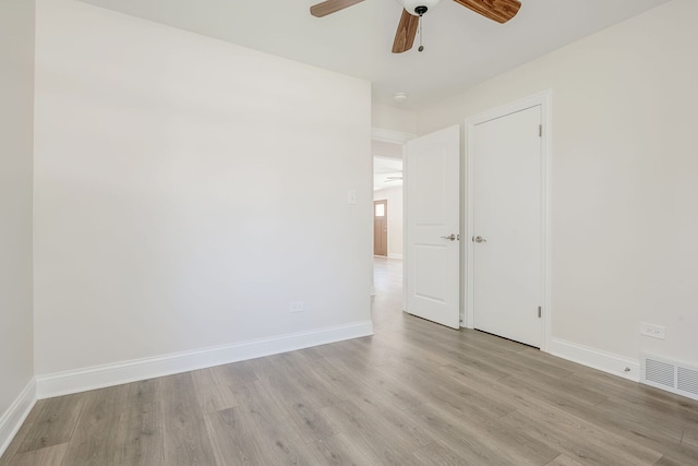 spare room featuring light wood-type flooring, a ceiling fan, and baseboards