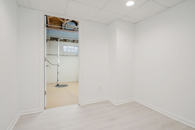empty room with light wood-style floors, baseboards, and a drop ceiling