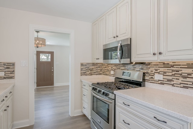kitchen with appliances with stainless steel finishes, light wood-style flooring, light countertops, tasteful backsplash, and baseboards