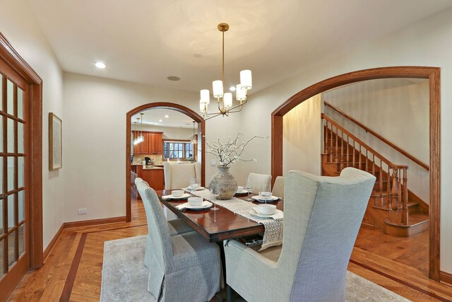 dining area featuring recessed lighting, a chandelier, arched walkways, and light wood-style flooring