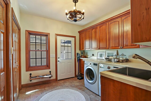 laundry area with stone tile floors, baseboards, cabinet space, a notable chandelier, and independent washer and dryer