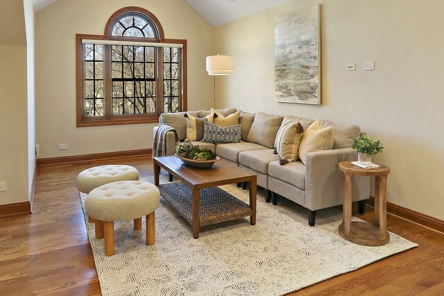 living area with wood finished floors, baseboards, and vaulted ceiling