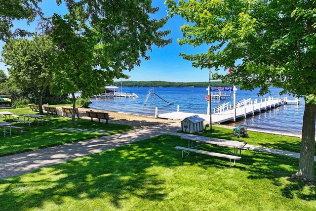 view of dock with a lawn and a water view