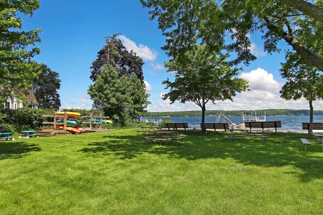 view of home's community with a yard, playground community, a boat dock, and a water view