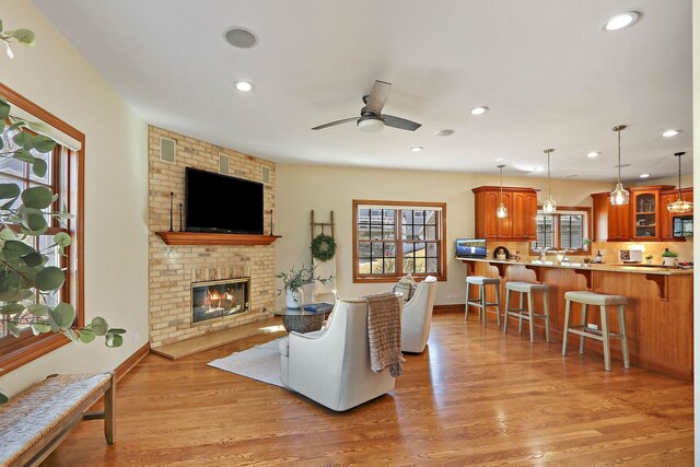 living room featuring recessed lighting, a brick fireplace, ceiling fan, and light wood finished floors