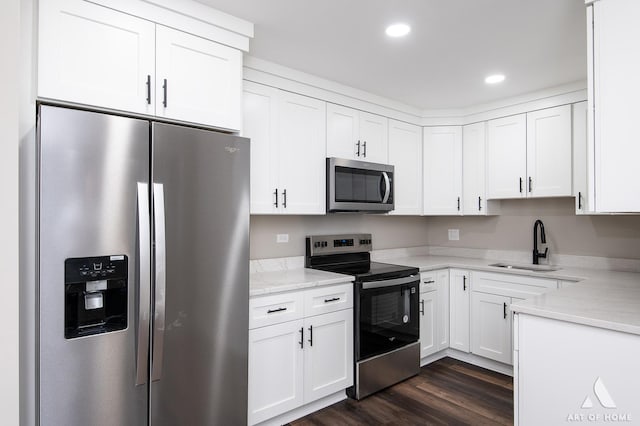 kitchen with a sink, appliances with stainless steel finishes, dark wood-style flooring, and white cabinetry