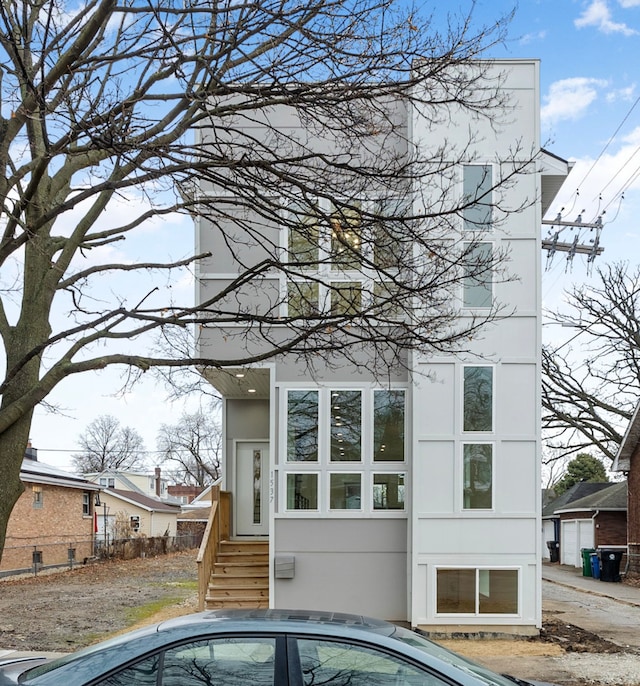 rear view of house featuring stucco siding and fence