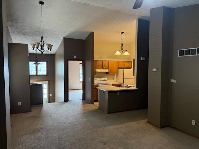 kitchen with visible vents, a peninsula, freestanding refrigerator, stove, and under cabinet range hood