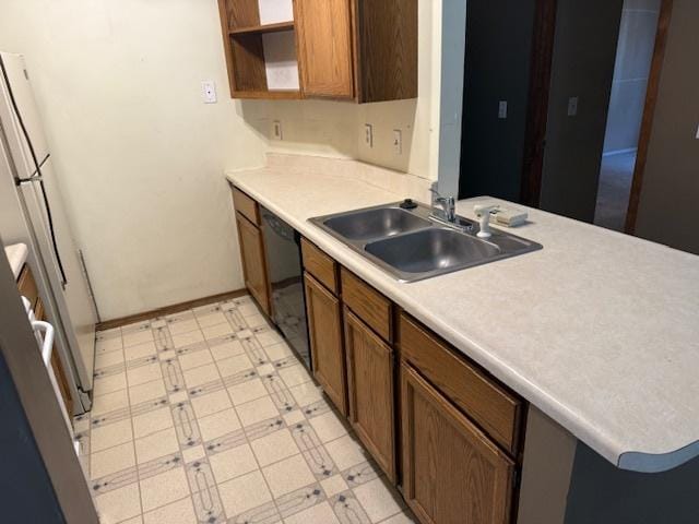 kitchen with light floors, refrigerator, a sink, light countertops, and black dishwasher