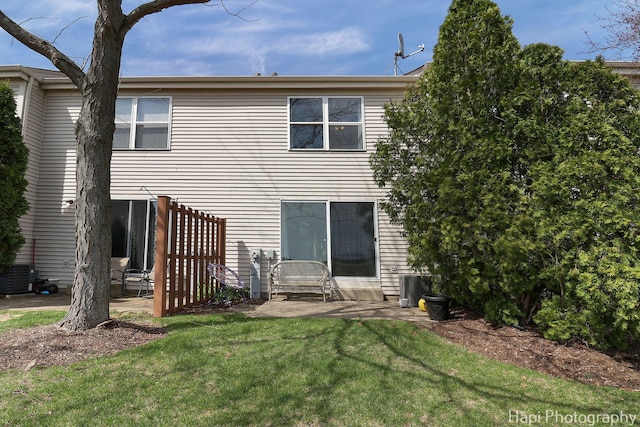 rear view of property featuring cooling unit, a patio area, and a lawn