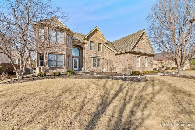 traditional-style house featuring brick siding and a front lawn