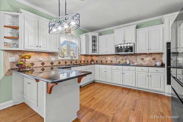 kitchen with a breakfast bar area, appliances with stainless steel finishes, a peninsula, and white cabinetry