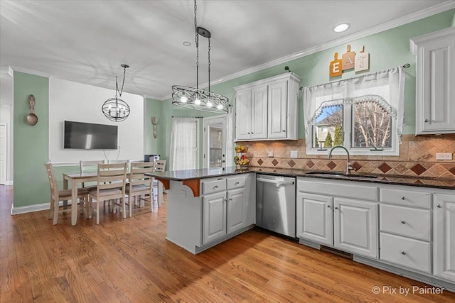 kitchen featuring light wood finished floors, a peninsula, stainless steel dishwasher, white cabinets, and a sink