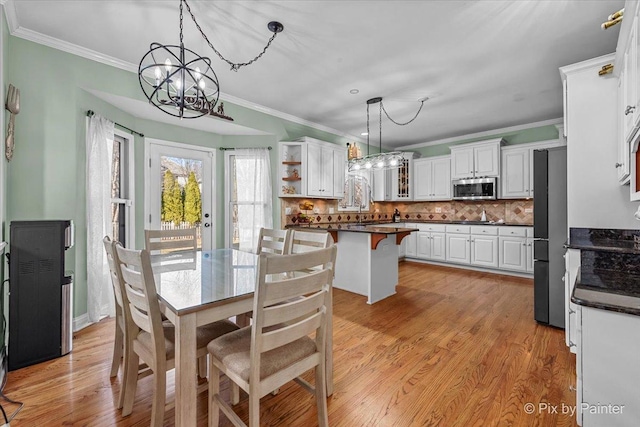 dining room with an inviting chandelier, light wood-style flooring, and ornamental molding