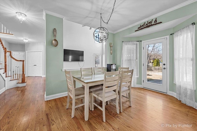 dining room with a notable chandelier, light wood-style floors, crown molding, baseboards, and stairs