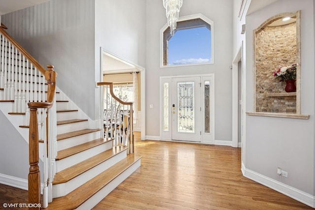 entrance foyer featuring stairway, baseboards, a towering ceiling, and wood finished floors