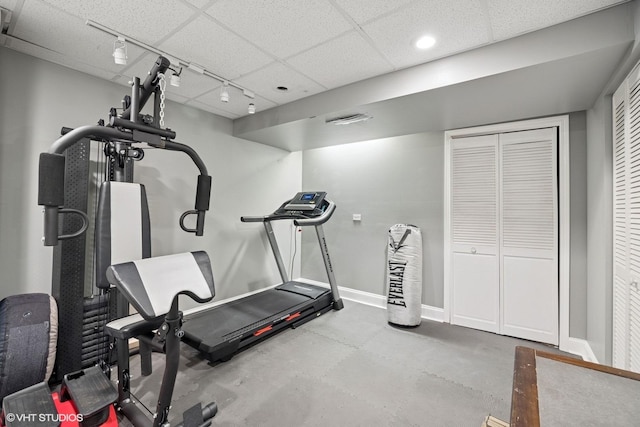 workout area with a drop ceiling, baseboards, and rail lighting