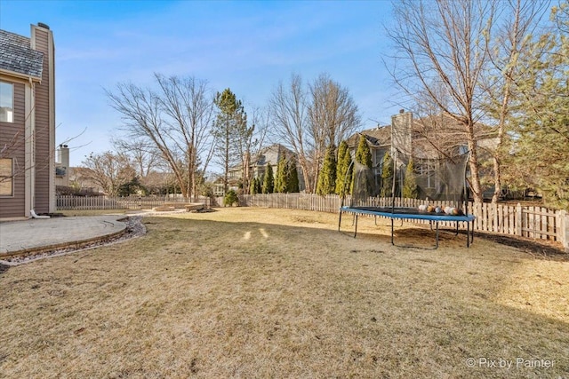 view of yard with a trampoline, a fenced backyard, and a patio area