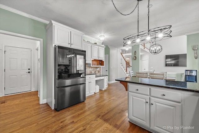 kitchen with light wood-style flooring, ornamental molding, tasteful backsplash, white cabinets, and refrigerator with glass door