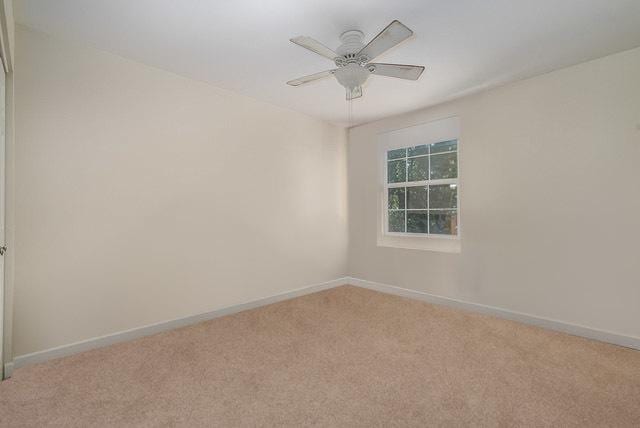 spare room with baseboards, light carpet, and a ceiling fan