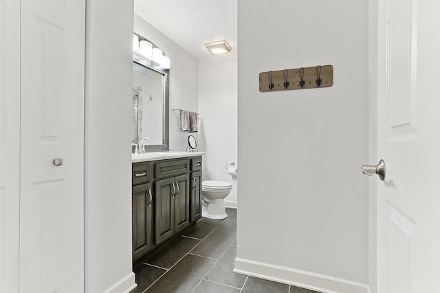 bathroom with baseboards, toilet, and vanity