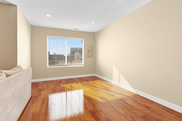 spare room with electric panel, visible vents, baseboards, and wood-type flooring