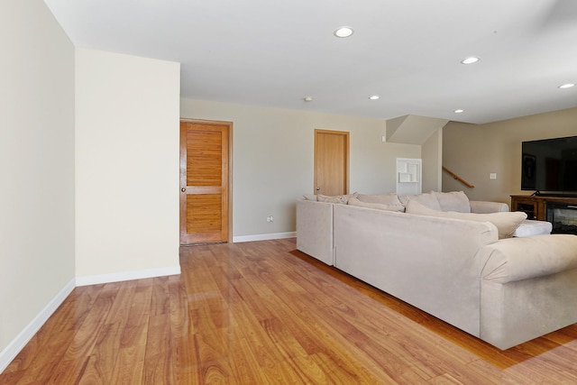 unfurnished living room featuring recessed lighting, baseboards, stairs, and light wood finished floors