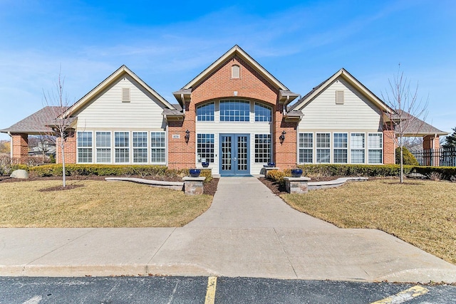 traditional-style home featuring french doors, brick siding, and a front yard