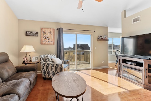 living room with visible vents, baseboards, wood finished floors, and a ceiling fan