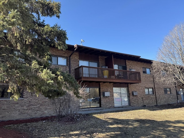 back of property featuring a balcony and brick siding