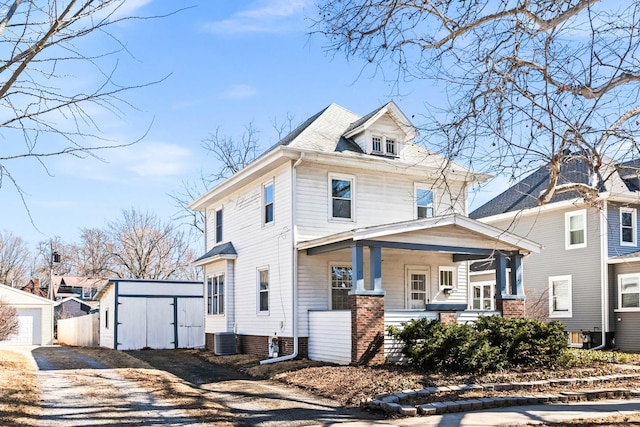 american foursquare style home featuring covered porch, cooling unit, a storage shed, and an outdoor structure