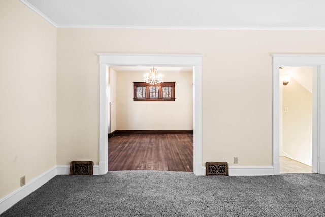 empty room with a notable chandelier, carpet, baseboards, and ornamental molding