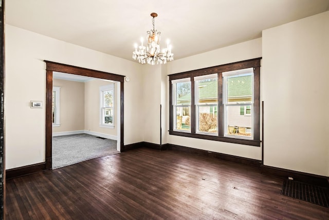 empty room with visible vents, baseboards, a notable chandelier, and dark wood-style flooring