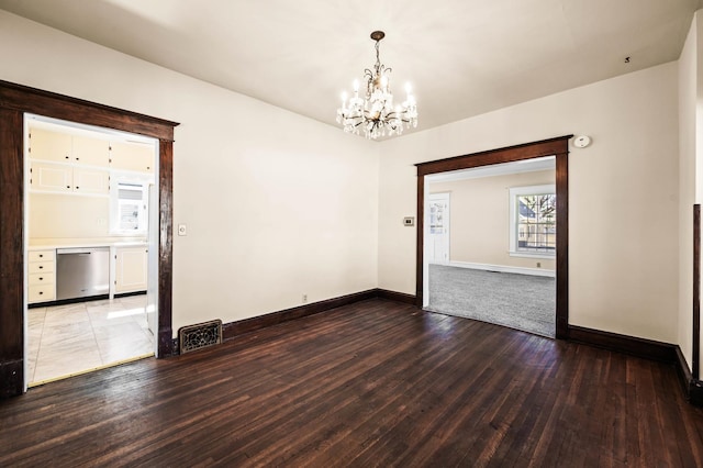 unfurnished room featuring visible vents, baseboards, hardwood / wood-style floors, and a chandelier