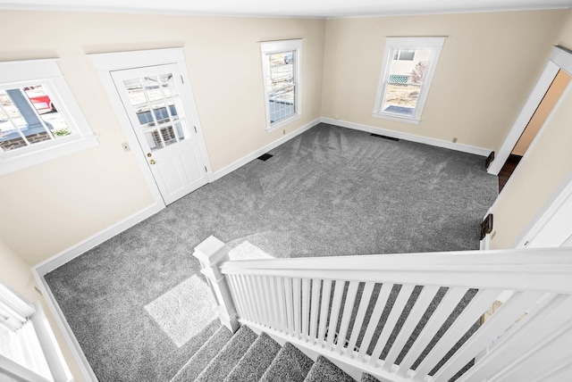 foyer featuring visible vents, dark carpet, stairs, and baseboards