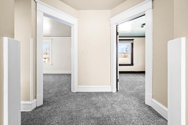 hall featuring carpet flooring and baseboards