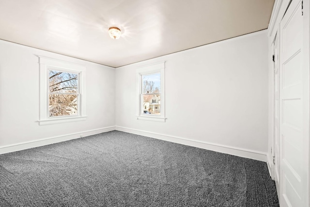 unfurnished bedroom featuring carpet flooring, multiple windows, and baseboards