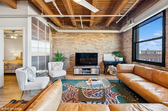 living area with visible vents, beam ceiling, wood finished floors, brick wall, and wooden ceiling