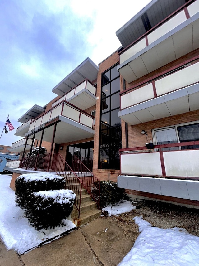 view of snowy exterior featuring brick siding