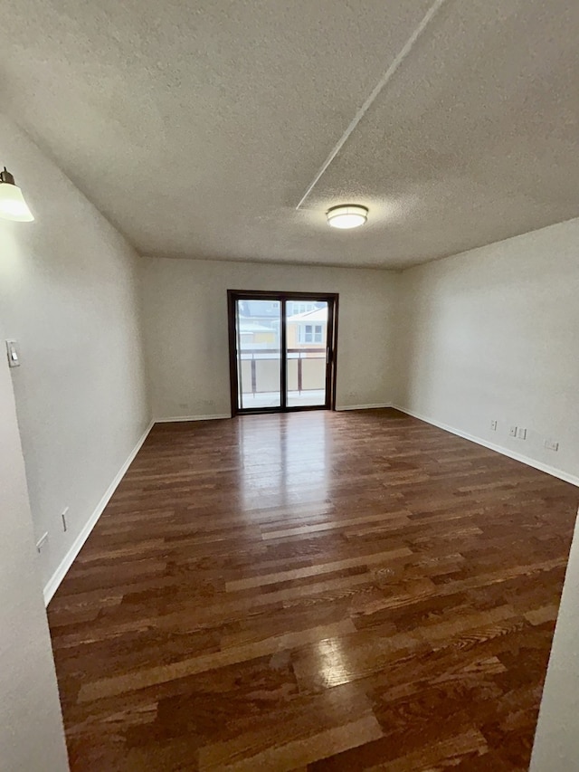 unfurnished room with wood finished floors, baseboards, and a textured ceiling