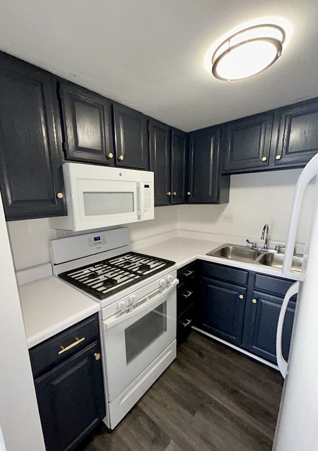 kitchen with white appliances, a sink, light countertops, dark wood-type flooring, and dark cabinets