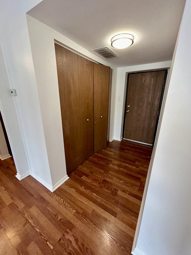 corridor with visible vents, baseboards, and wood finished floors