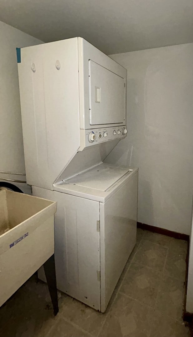 laundry room featuring laundry area, stacked washer / drying machine, and a sink