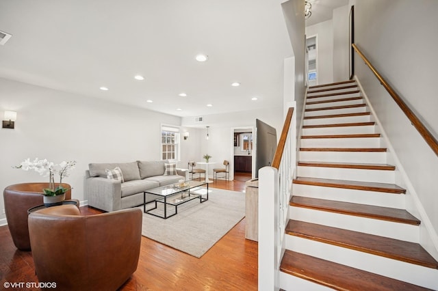 living room featuring recessed lighting, visible vents, stairs, and light wood finished floors