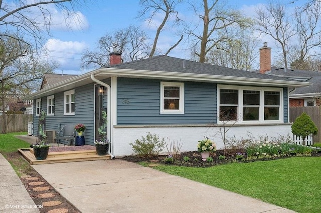 view of property exterior with a chimney, brick siding, fence, and a yard