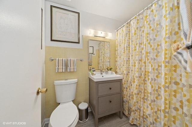 full bath featuring vanity, toilet, curtained shower, and tile walls
