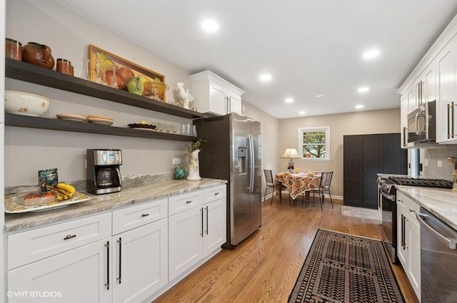 kitchen featuring recessed lighting, stainless steel appliances, open shelves, light wood-style floors, and white cabinets